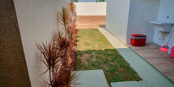 Área de serviço da casa modelo do San Gabriel Residence. Apresenta um jardim próximo a parede e um espaço com um tanque.